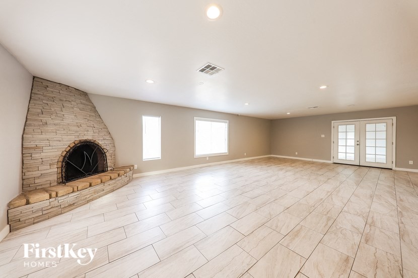an empty living room with a fireplace and tiled floors