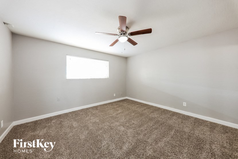 a carpeted room with a ceiling fan and a window