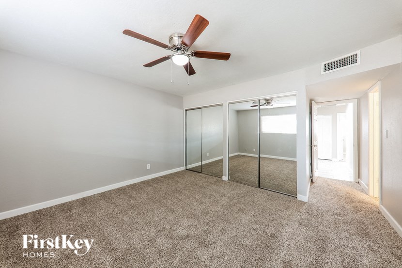 a bedroom with a ceiling fan and a mirrored closet