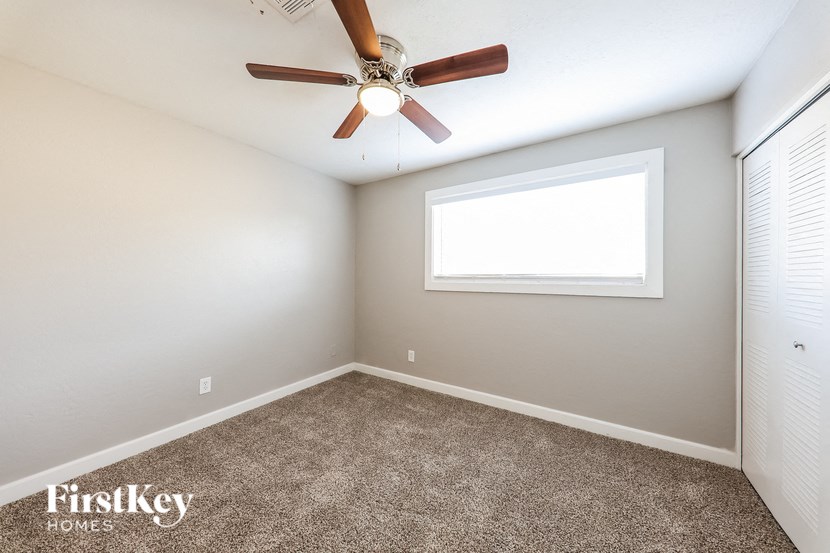 an empty room with a ceiling fan and a window