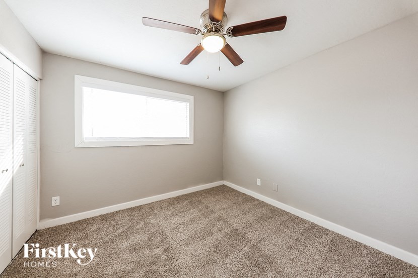 an empty room with a ceiling fan and a window