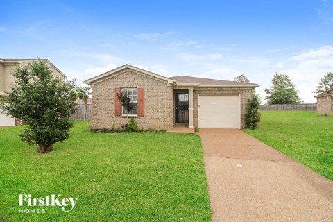 a small brick house with a lawn and a driveway