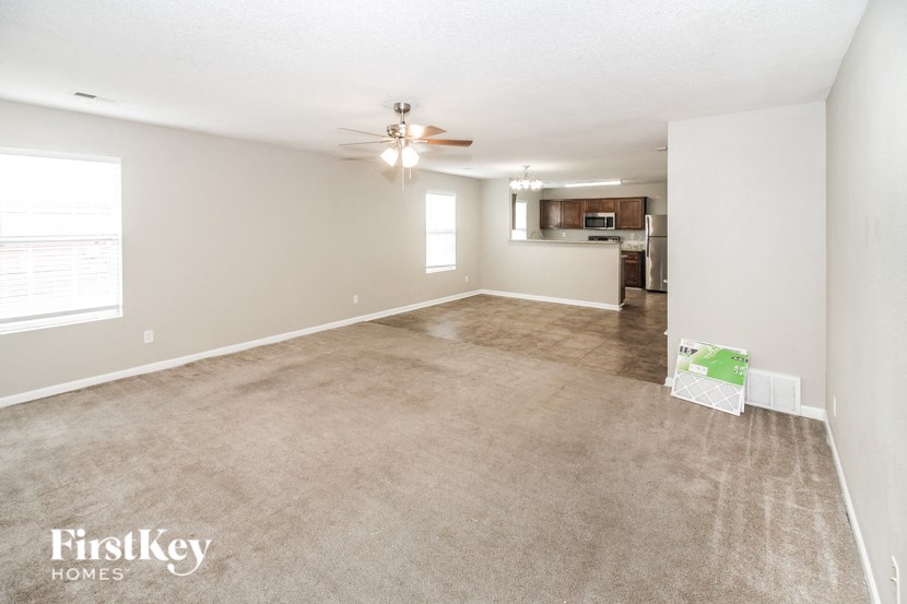 the spacious living room with carpet and a ceiling fan