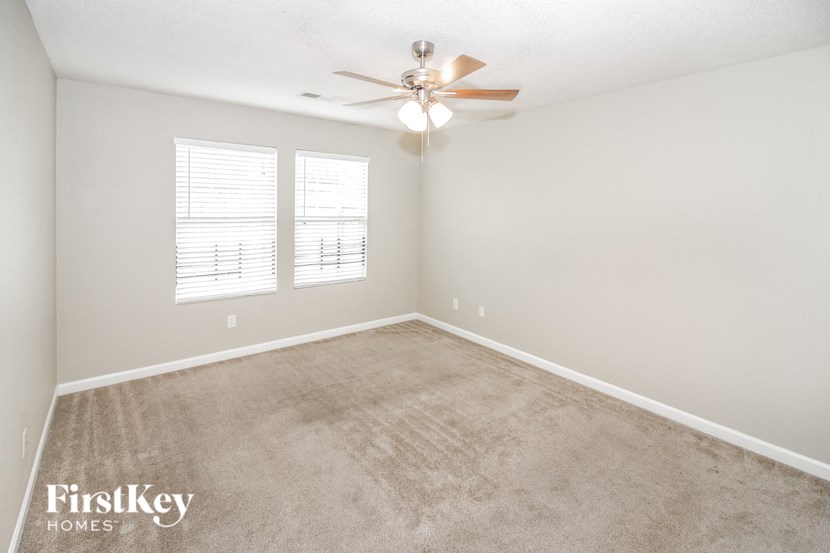 a bedroom with a carpeted floor and a ceiling fan