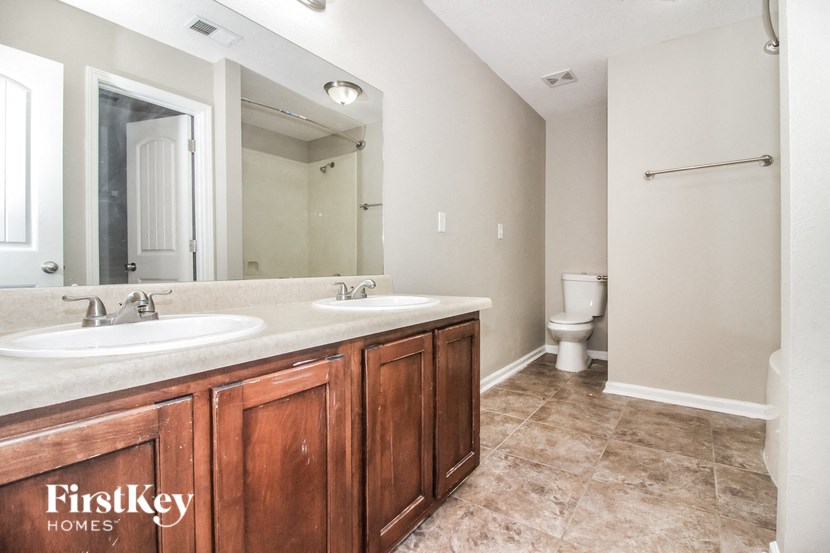 the master bathroom has two sinks and a large mirror