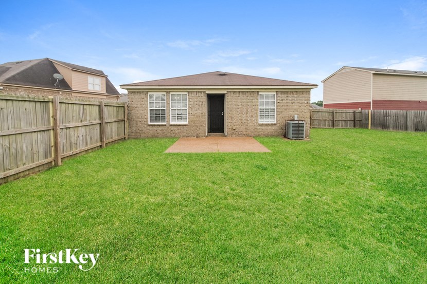 a backyard with a brick house and a fenced in yard