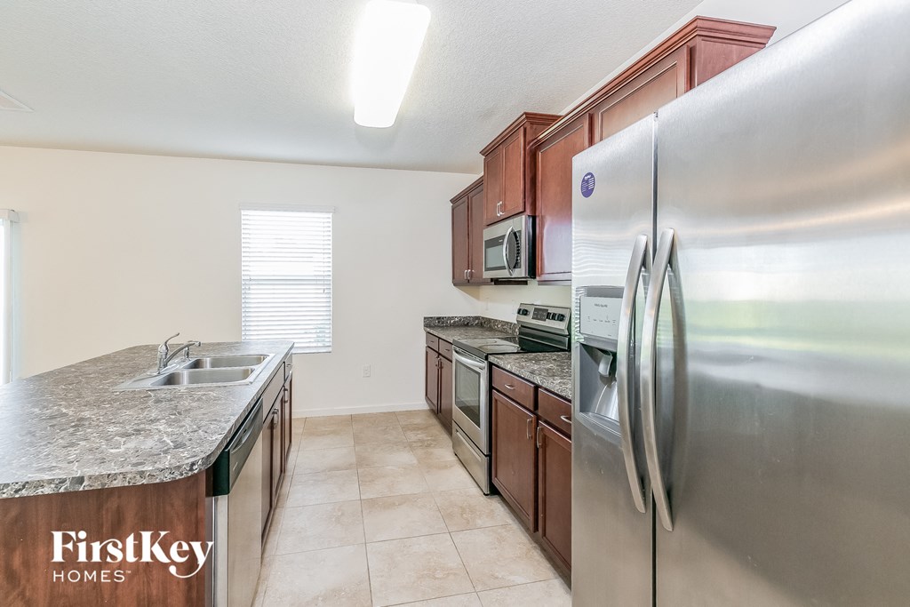 A kitchen with a stainless steel refrigerator and a granite countertop.
