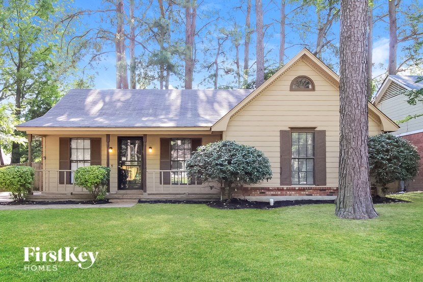 A house with a porch and a tree in front of it.