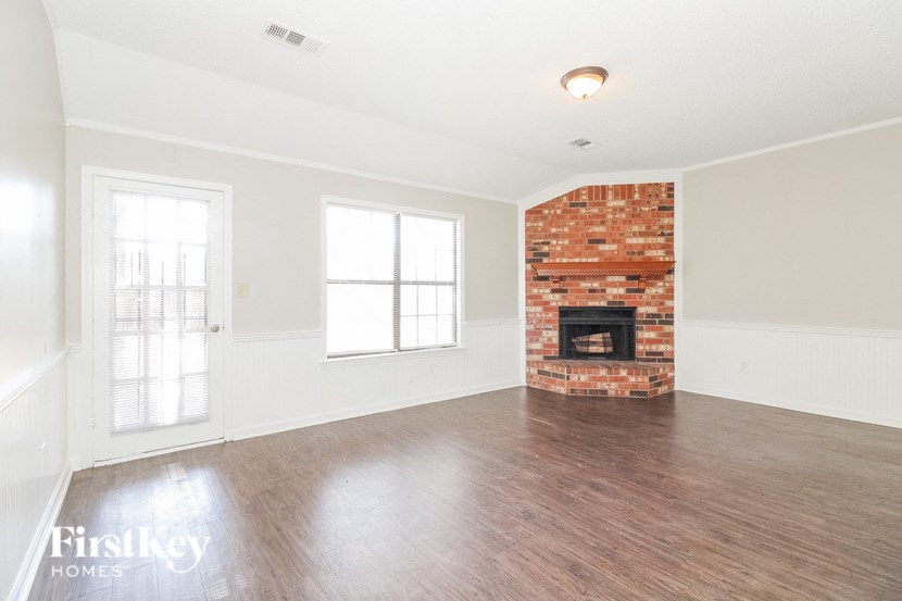 A room with a brick fireplace and wooden floors.