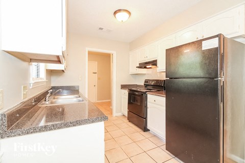 A kitchen with a black fridge and a black stove top oven.