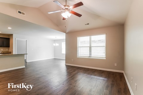A spacious room with a ceiling fan and wooden flooring.