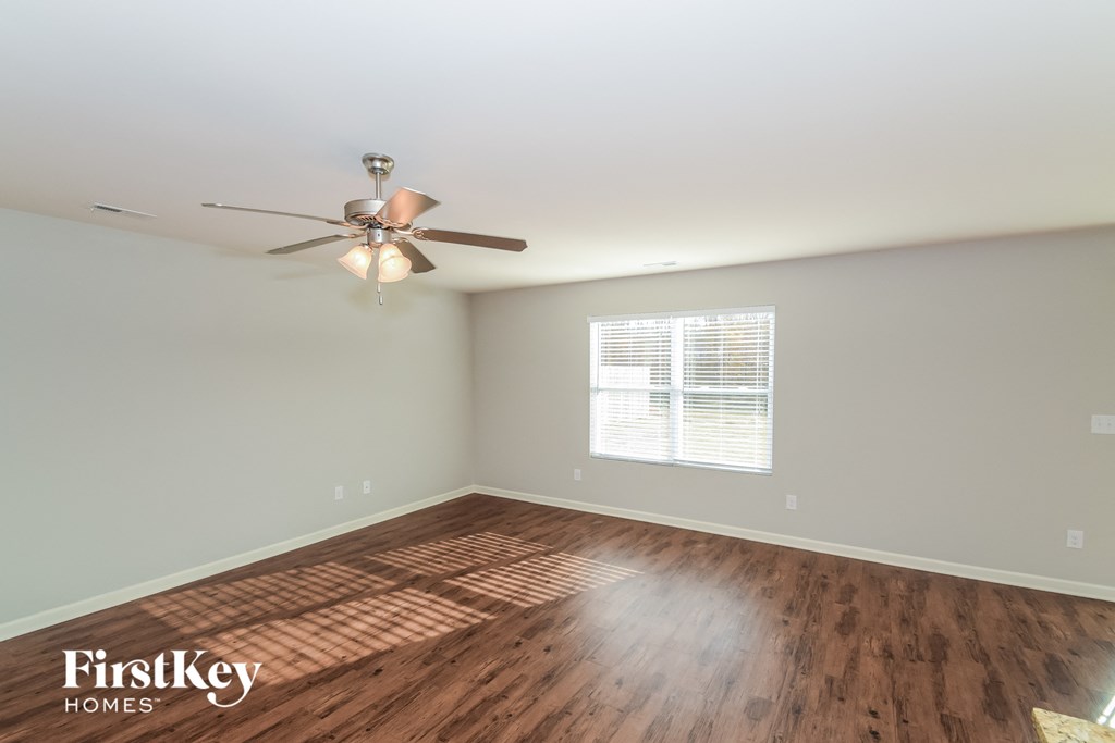 A room with a ceiling fan and wooden flooring.