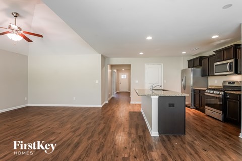 A kitchen with a white counter top and wooden floors.