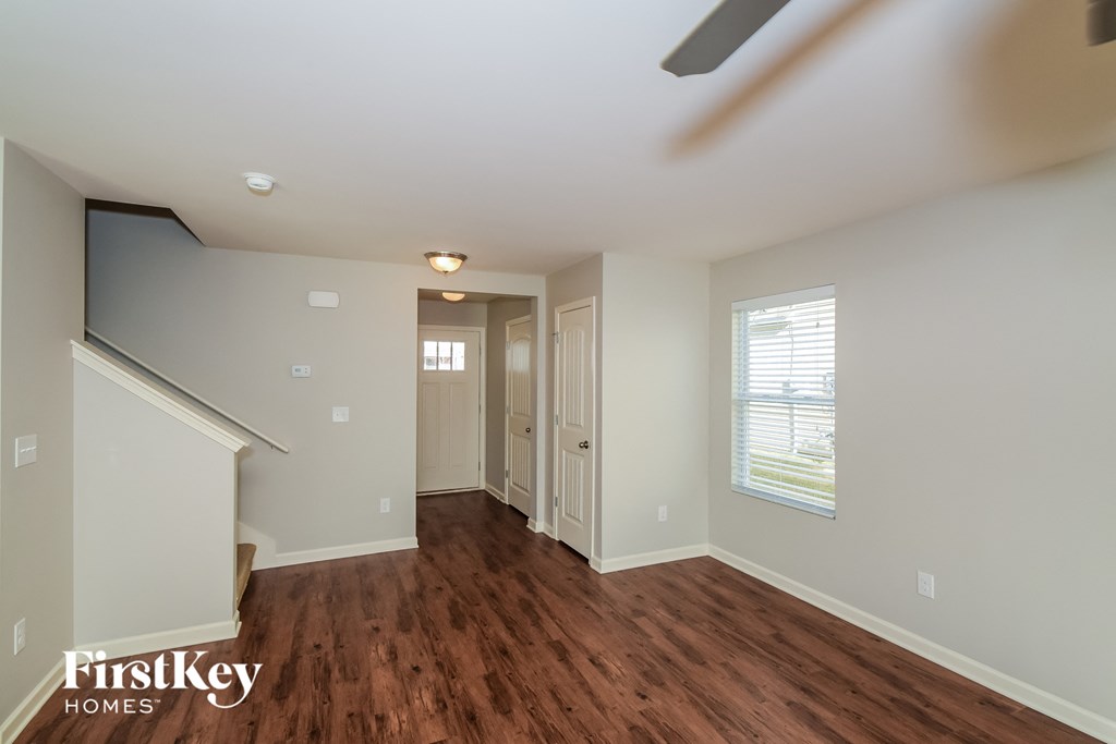 A room with wooden floors and a staircase leading to another room.