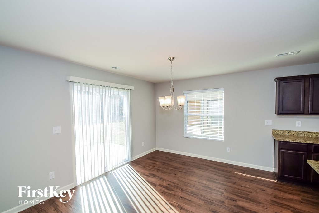 A well-lit room with wooden floors and a chandelier hanging from the ceiling.
