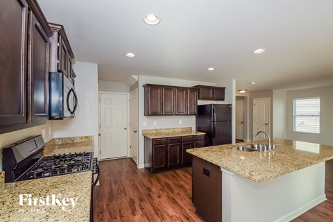 A kitchen with a granite countertop and a stove top oven.