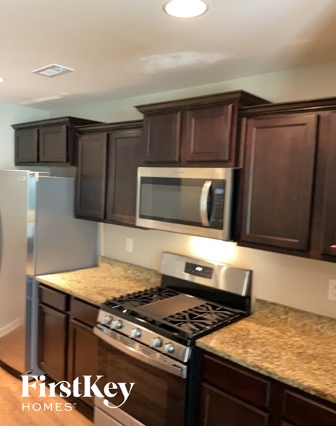 A kitchen with brown cabinets and a stove top oven.