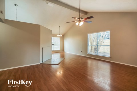 A spacious room with wooden floors and a ceiling fan.