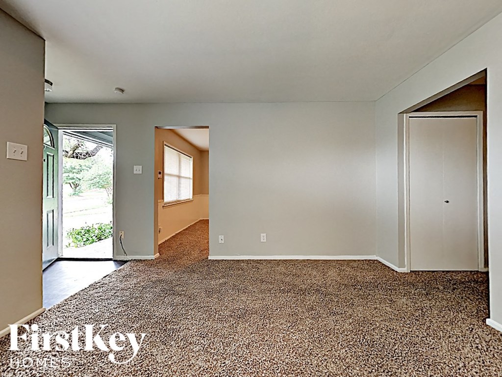 an empty living room with a door to a hallway