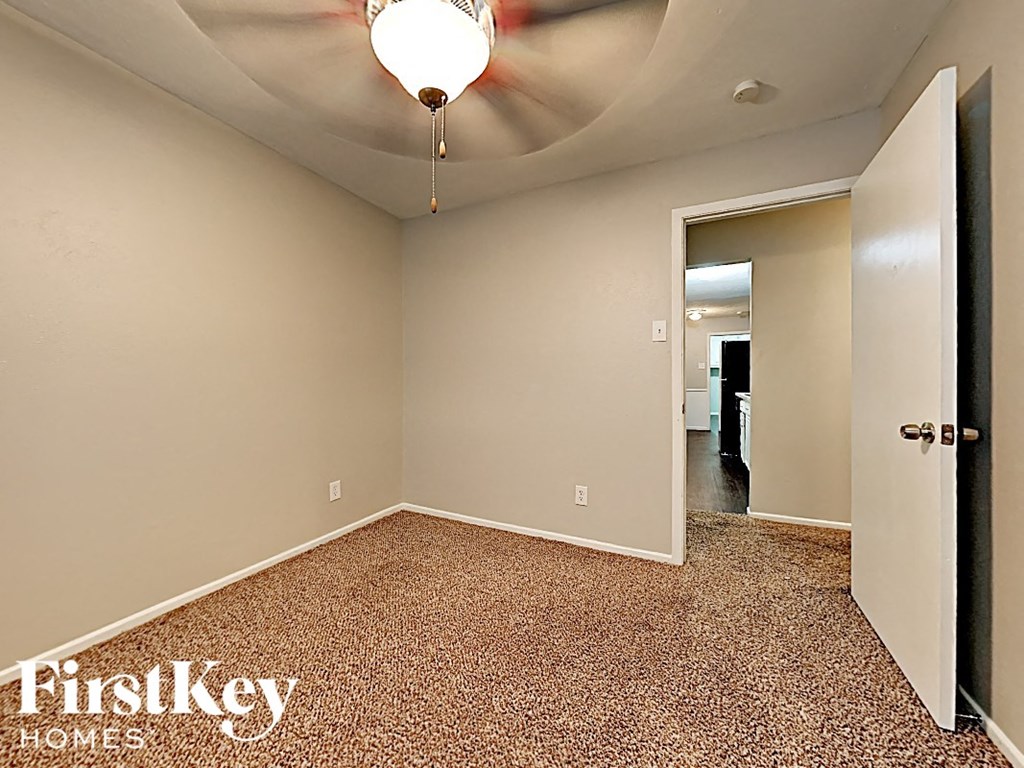 a bedroom with a ceiling fan and a door to a hallway