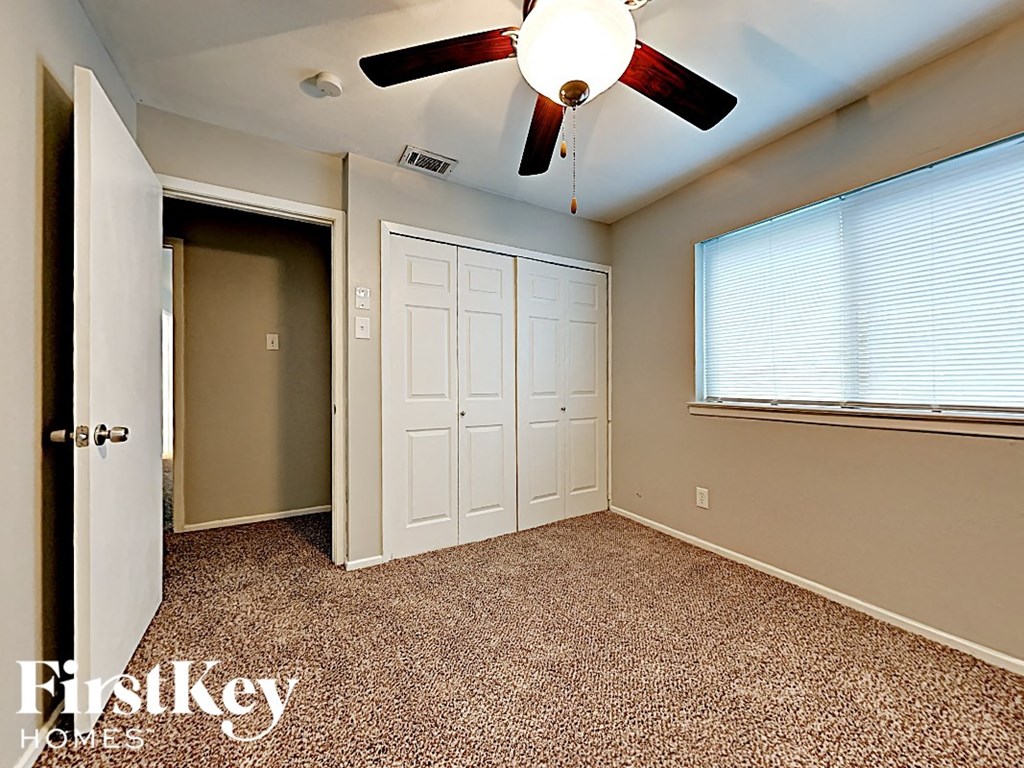 an empty bedroom with a ceiling fan and a closet