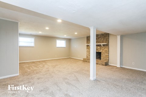 A spacious room with a stone fireplace and carpeted floor.