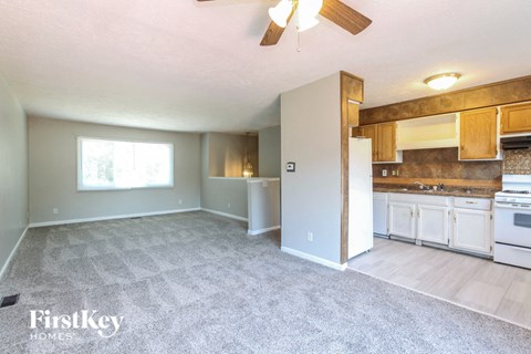 A spacious living room with a kitchen area in the background.