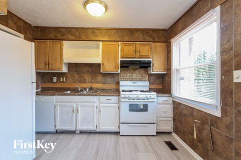 A kitchen with white appliances and wooden cabinets.