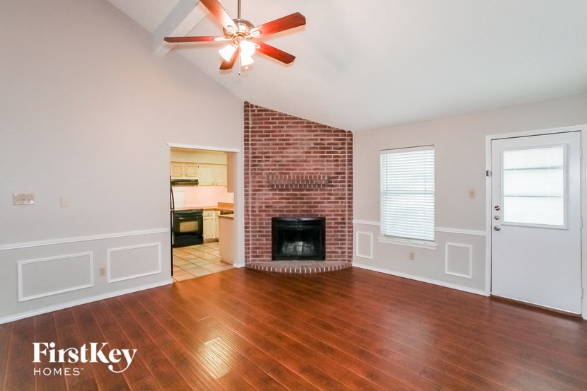 an empty living room with a brick fireplace and wooden floors