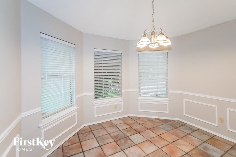 an empty dining room with three windows and a chandelier