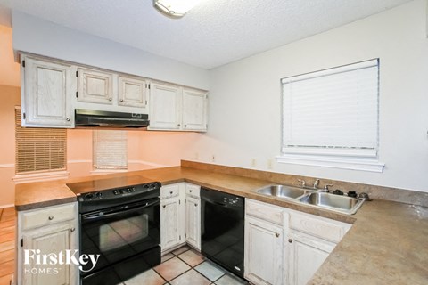 a kitchen with white cabinets and black appliances and a sink