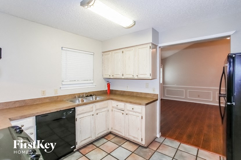 a kitchen with white cabinets and a sink and a refrigerator