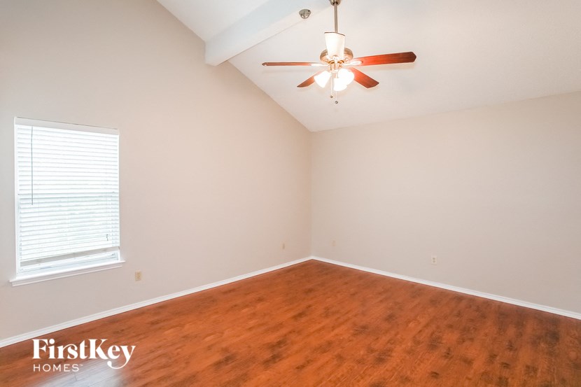 a bedroom with wood flooring and a ceiling fan