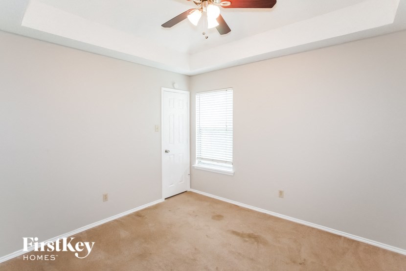 a bedroom with white walls and a ceiling fan