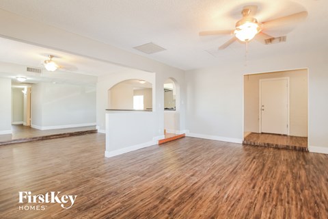 the living room and dining room with wood flooring and a ceiling fan