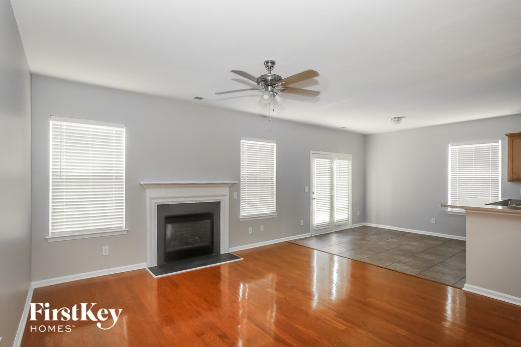 A spacious living room with a fireplace and a ceiling fan.
