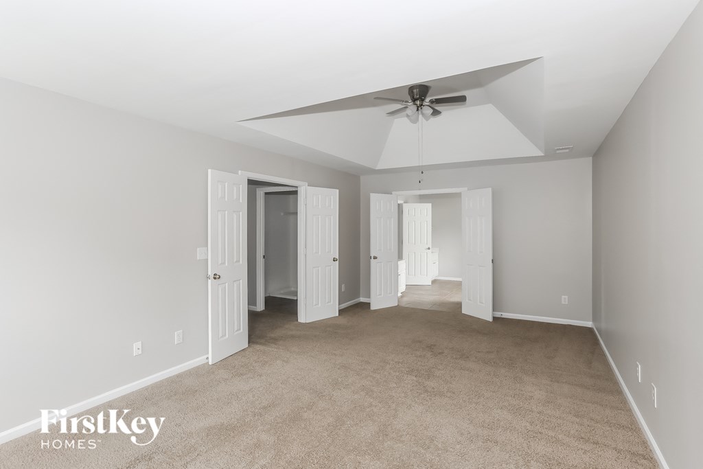 A spacious room with a carpeted floor and a ceiling fan.