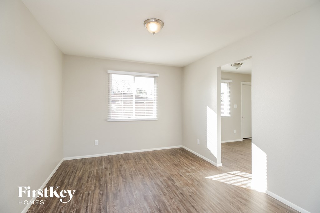 a spacious living room with hardwood flooring and white walls