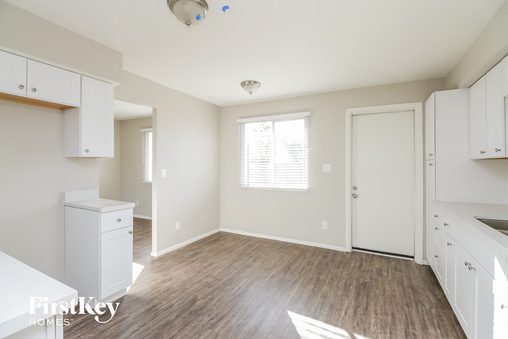 a kitchen and dining room with white cabinets and wood flooring