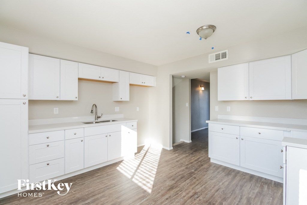 a large white kitchen with white cabinets and wood flooring