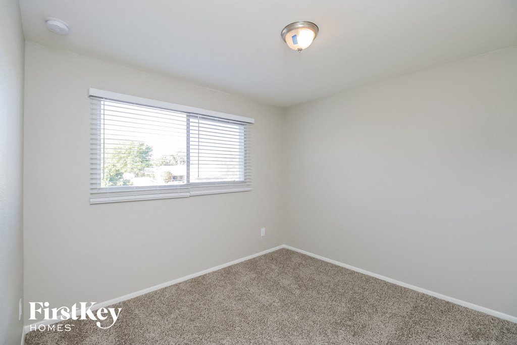 a bedroom with white walls and a window and carpet