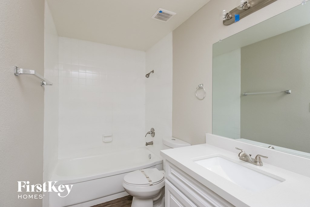 a white bathroom with a white sink and toilet and a bath tub
