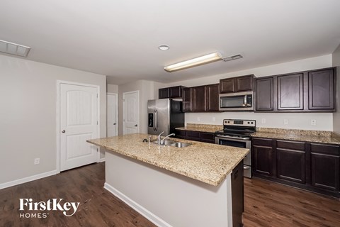 a kitchen with granite countertops and dark wood cabinets