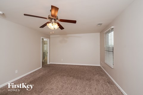 the spacious living room with ceiling fan and carpet