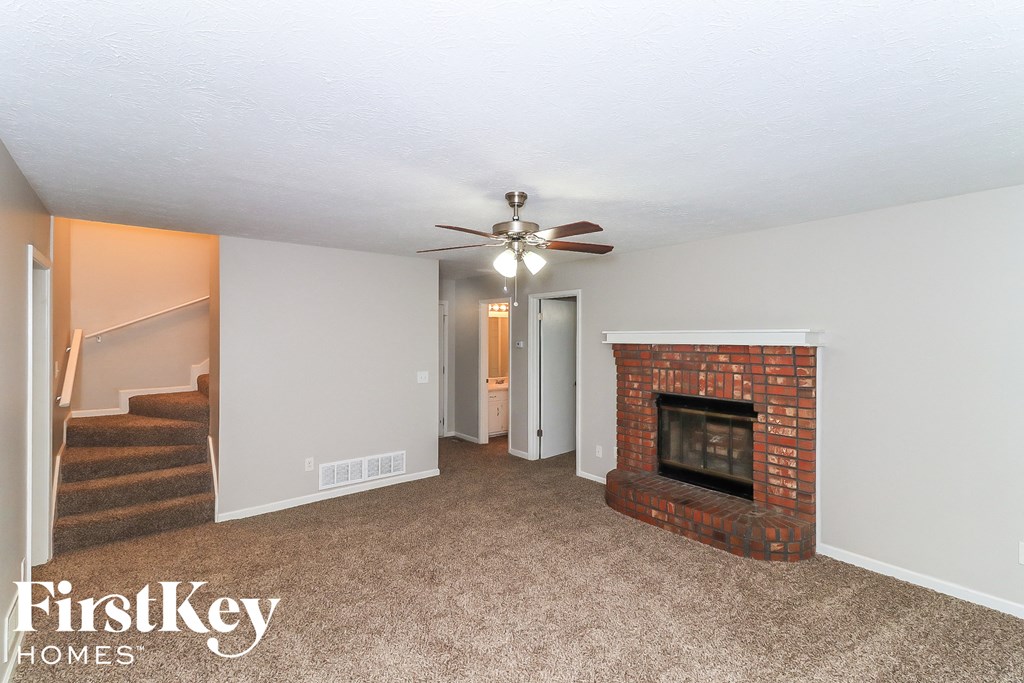 A living room with a fireplace and a ceiling fan.