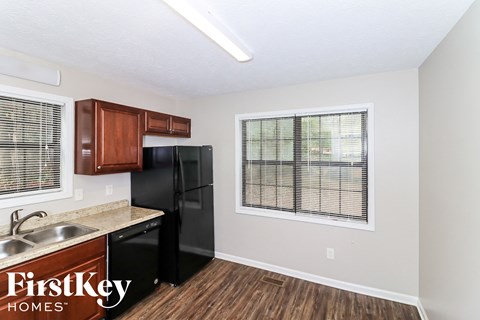 A kitchen with a black refrigerator and wooden cabinets.