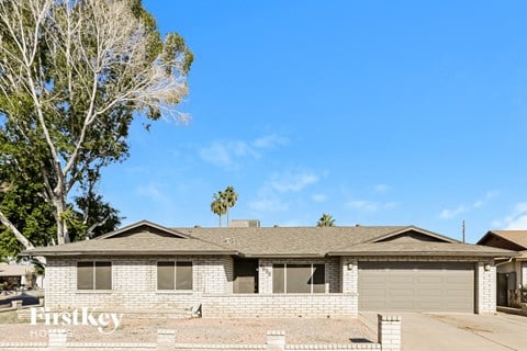 a white brick house with a tree and a blue sky