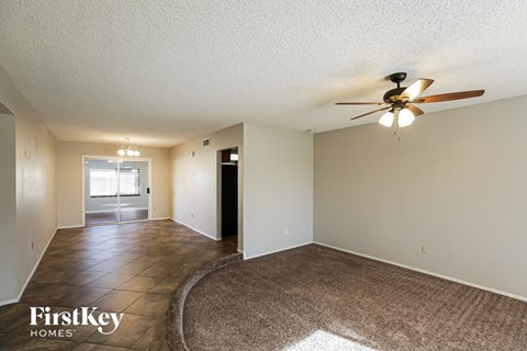 a spacious living room with a large rug and a ceiling fan