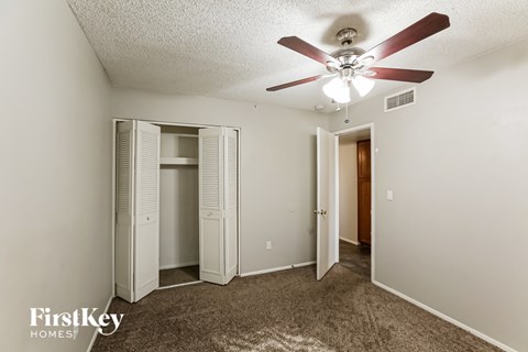 a bedroom with a ceiling fan and a closet