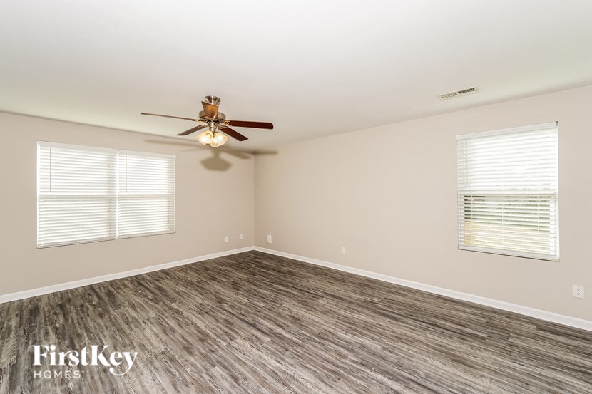 A room with a ceiling fan and two windows.